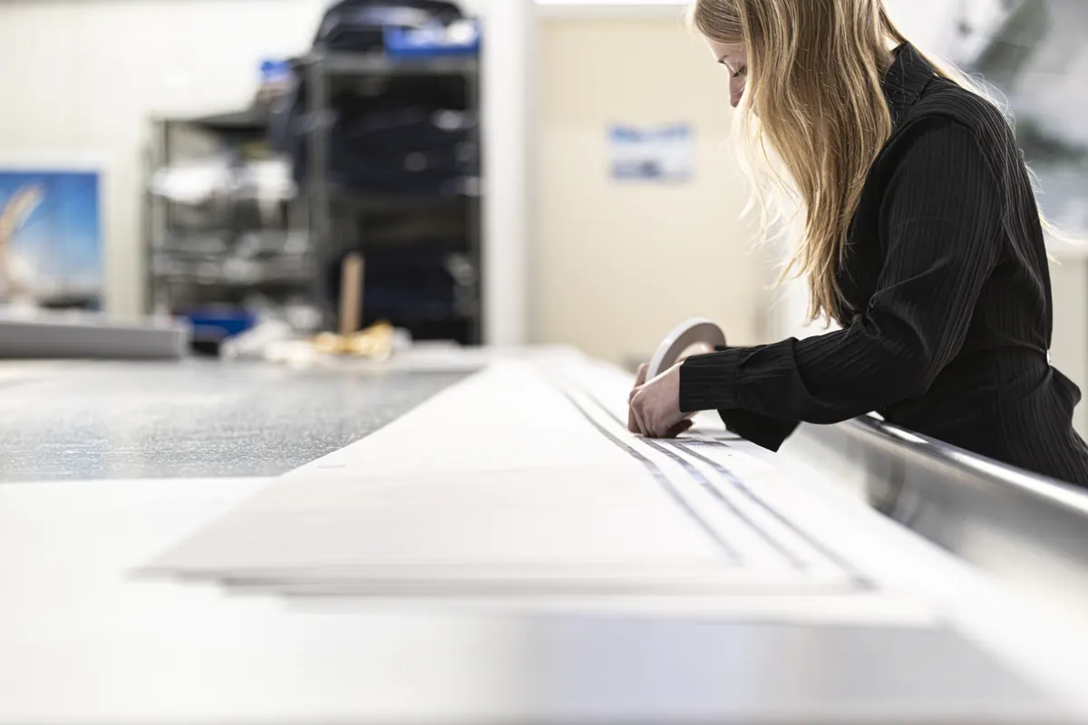 Naden van een zeil worden op de werktafel geplakt